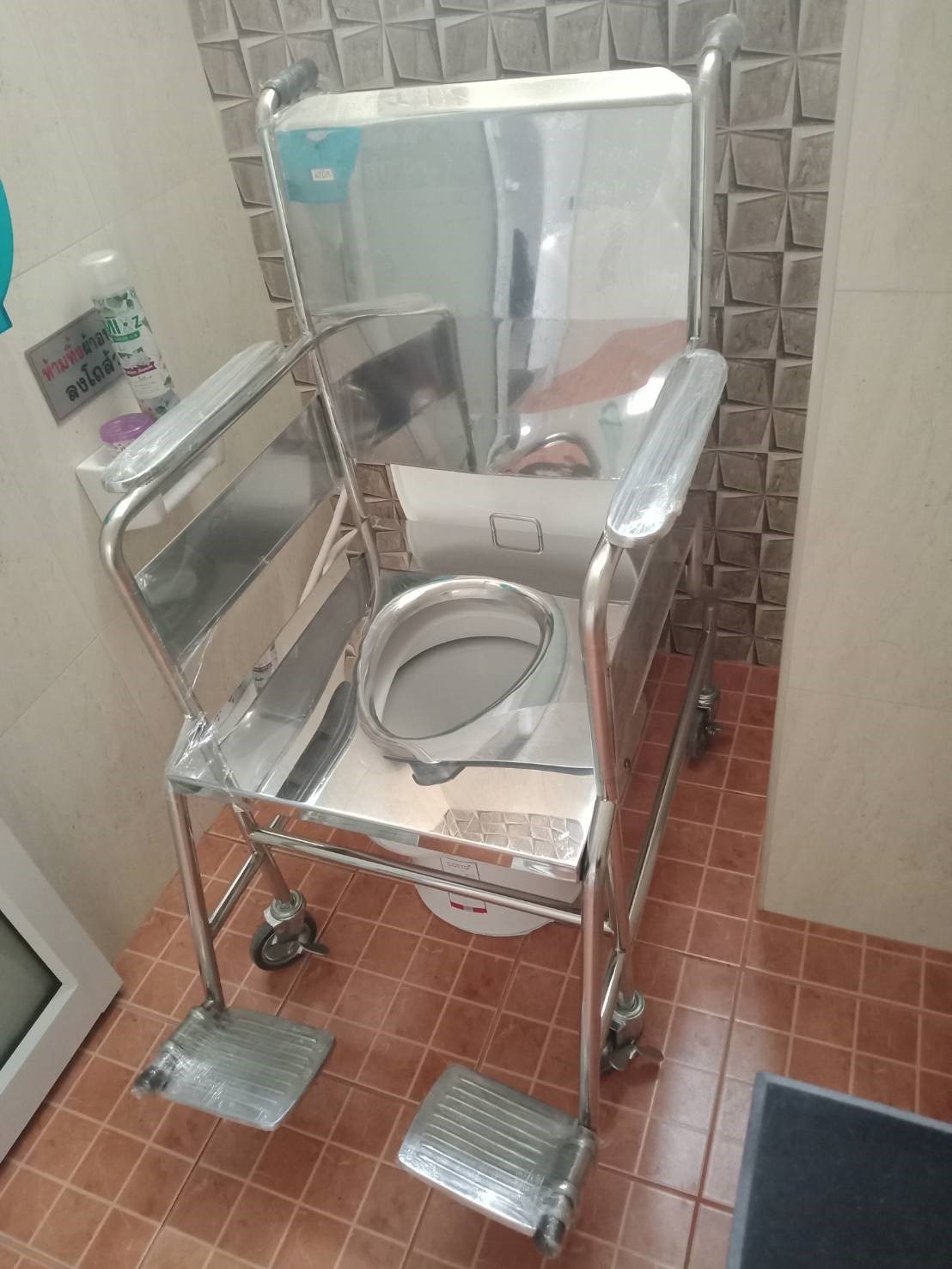 รถเข็นวีลแชร์นั่งถ่ายสแตนเลส รุ่น PS101 แบบพับไม่ได้ พร้อมเบาะรองนั่ง และถังรองถ่าย (ล้อหลังเล็ก)
