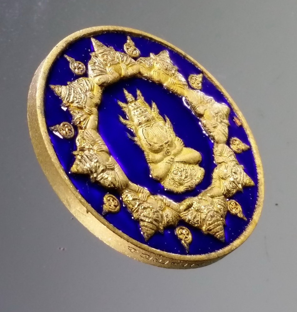 รหัสสินค้า จตุคามรามเทพ 211 เหรียญกะไหล่ทองลงยาสีน้ำเงิน พระปิดตาพังพระกาฬ รุ่นจอมจักรพรรดิ์มหาบารมี พ่อท่านนวล วัดไสหร้า ปลุกเสก สร้างปี 2550 โค้ด หมายเลข 1805 อยู่ที่ขอบเหรียญ