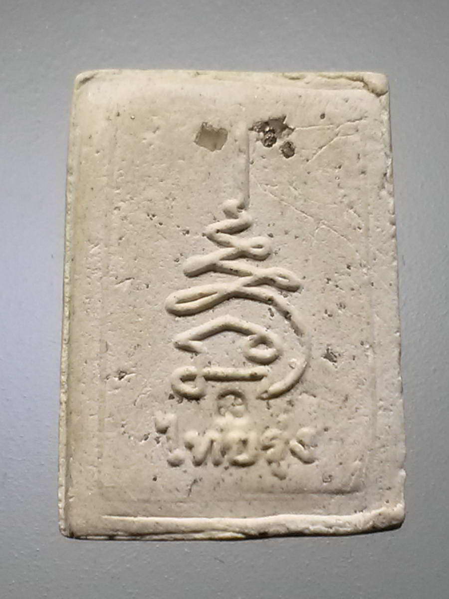 รหัสสินค้า พระสมเด็จวัดต่างๆ 989 พระสมเด็จพิมพ์คะแนน ฝังแร่มวลสาร และเพชรหน้าทั่ง ด้านหลังมีคำอักษรว่า ไทยรุ่ง และยันต์นะเฉลียวเพชร ไม่ทราบที่