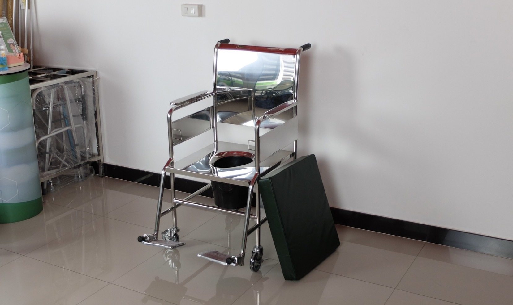 รถเข็นวีลแชร์นั่งถ่ายสแตนเลส รุ่น PS101 แบบพับไม่ได้ พร้อมเบาะรองนั่ง และถังรองถ่าย (ล้อหลังเล็ก)