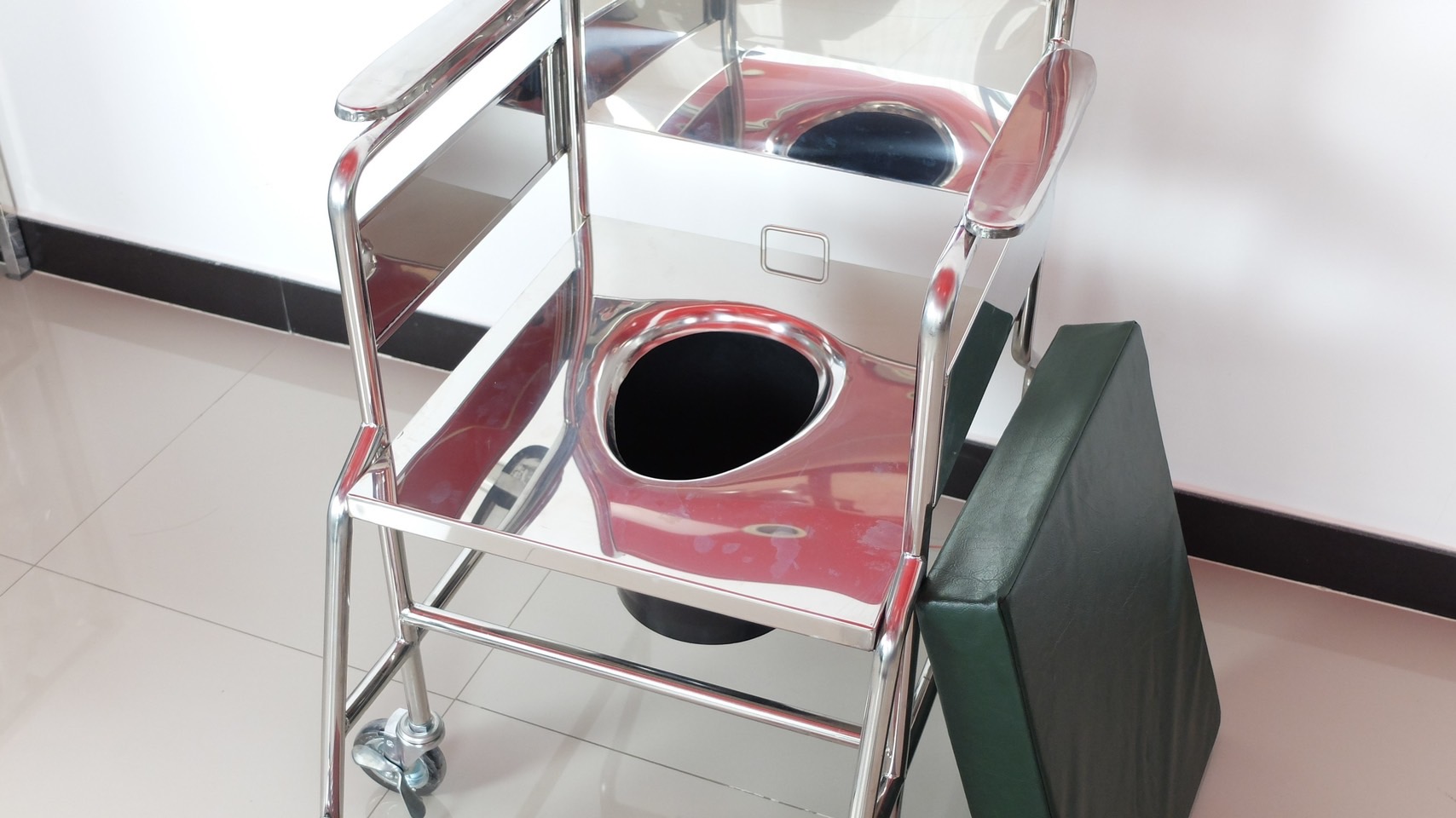 รถเข็นวีลแชร์นั่งถ่ายสแตนเลส รุ่น PS101 แบบพับไม่ได้ พร้อมเบาะรองนั่ง และถังรองถ่าย (ล้อหลังเล็ก)